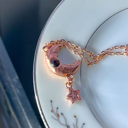 Man in Moon Star Pendant Copper Cultured Opal; necklace sitting on china plate, opal side up view 2