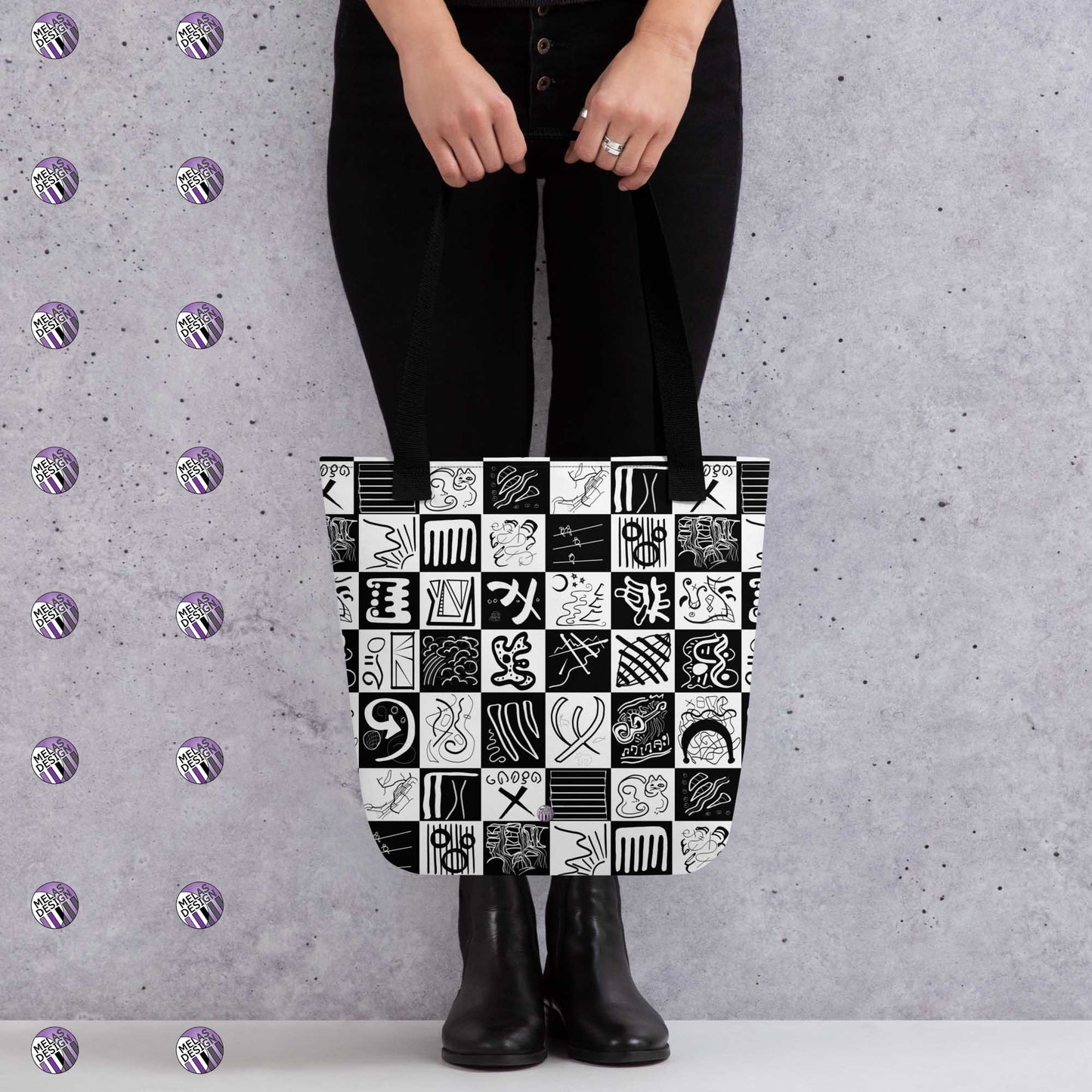 Melakandinsky Checkered Abstract Tote Bag; mock-up with model holding tote in front standing by gray wall with Melasdesign logos